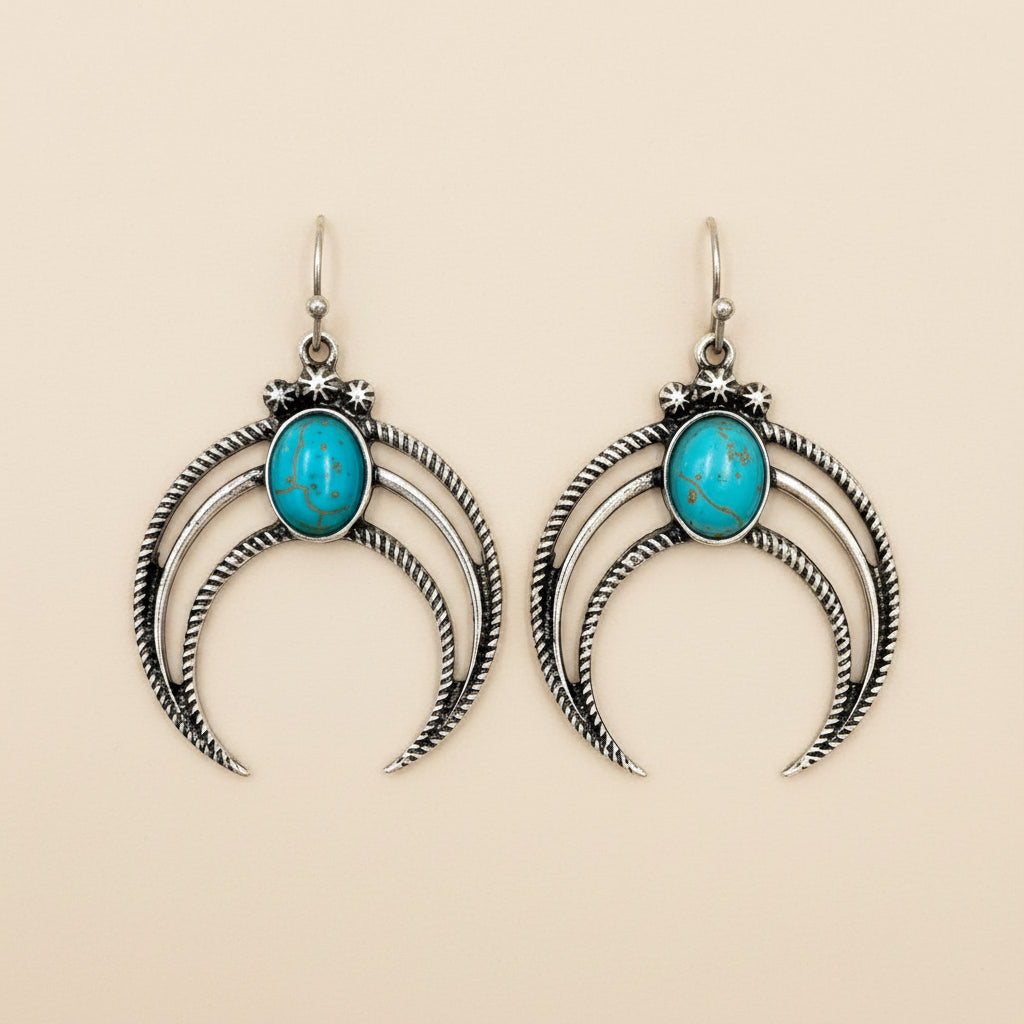 Silver crescent moon earrings with turquoise stones on a white background