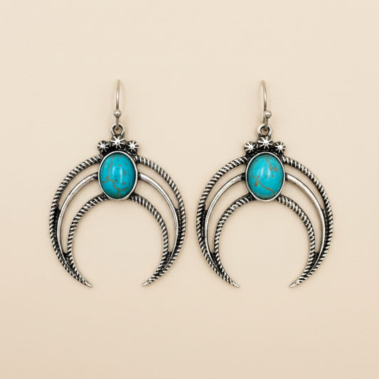 Silver crescent moon earrings with turquoise stones on a white background